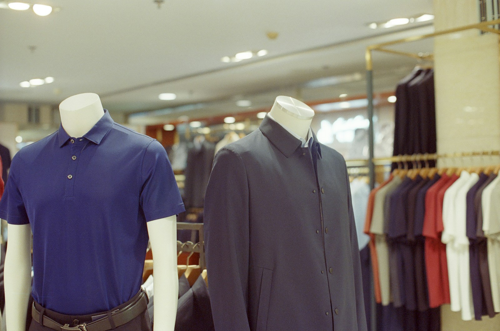 Two mannequins display men's clothing in a store.