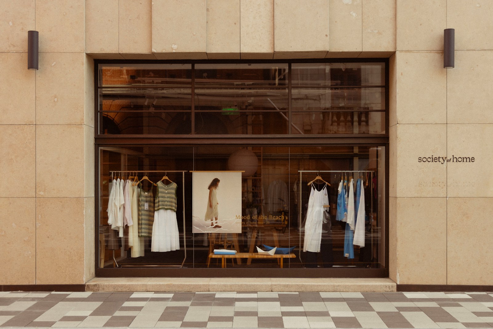 Clothing store window display with mannequins and racks.